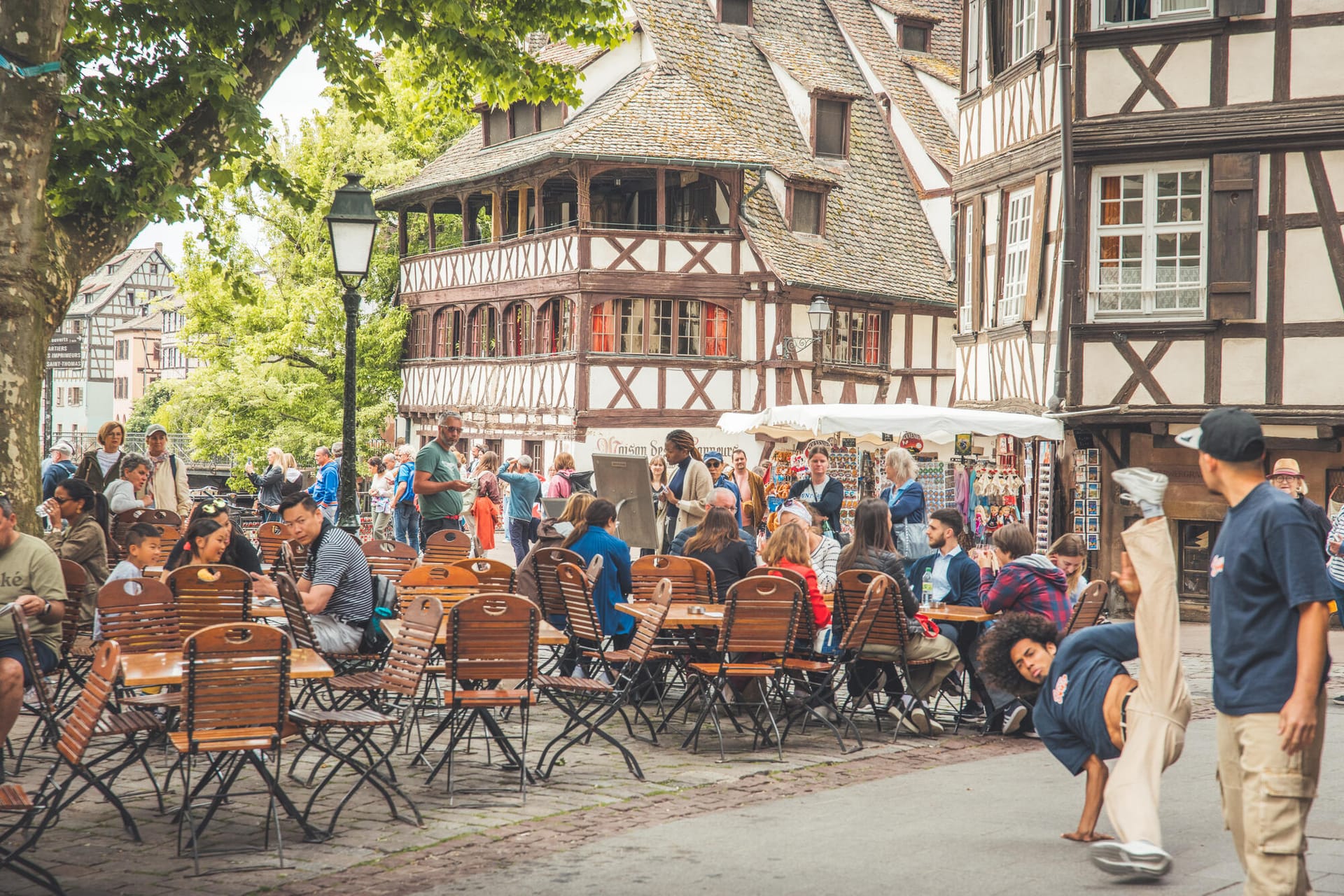 Scène de convivialité en terrasse dans le quartier de la Petite France à Strasbourg, un danseur au milieu de la foule